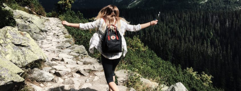 Woman with backpack hiking along mountain ridge